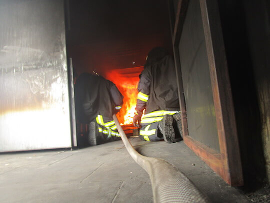 Feuerwehrangehörige spüren die Hitze des Feuers und Wasserdampf